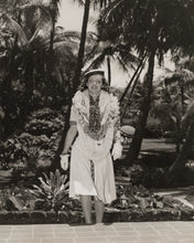 Load image into Gallery viewer, Black and white vintage photo of young Bette Davis wearing multiple lei with a tropical setting behind her.