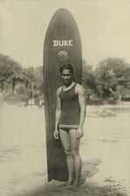 Load image into Gallery viewer, Photograph in light brown sepia tones of famous swimmer and surfer from Hawaii, Duke Kahanamoku standing in front of a sufrboard with "Duke" written on it.