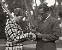 Load image into Gallery viewer, Black and white photo of Amelia Earhart and Duke Kahanamoku holding a pineapple.