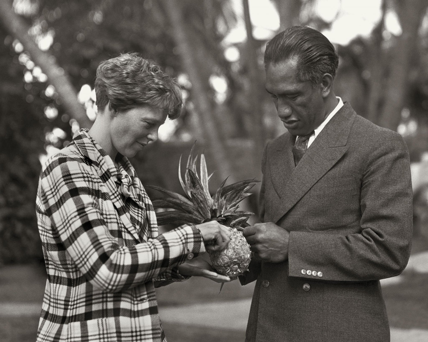 Black and white photo of Amelia Earhart and Duke Kahanamoku holding a pineapple.