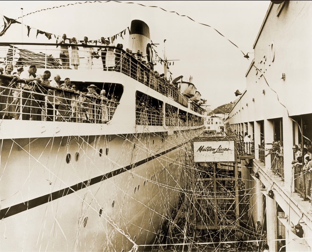 Black and white photograph of steamship at dock with passengers on decks and streamers coming from the ship and a sign reading Matson Lines in the middle of the photo.