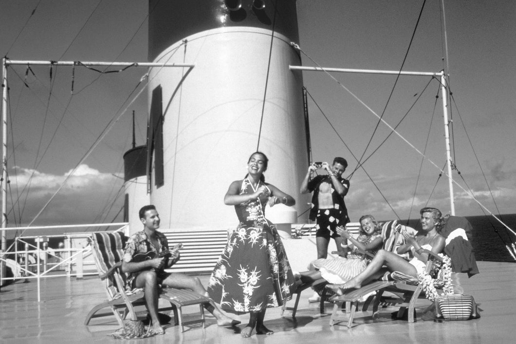 Black and white photo of a woman hula dancing on a cruise ship deck while others look on. Set in the 1950s.