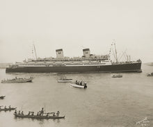 Load image into Gallery viewer, Photograph of a large cruise ship with two smokestacks. Several smaller boats and outrigger canoes float near the ship. Brown sepia tone. Signature on bottom right corner reads &#39;Edgeworth Photo M - 3&#39;.