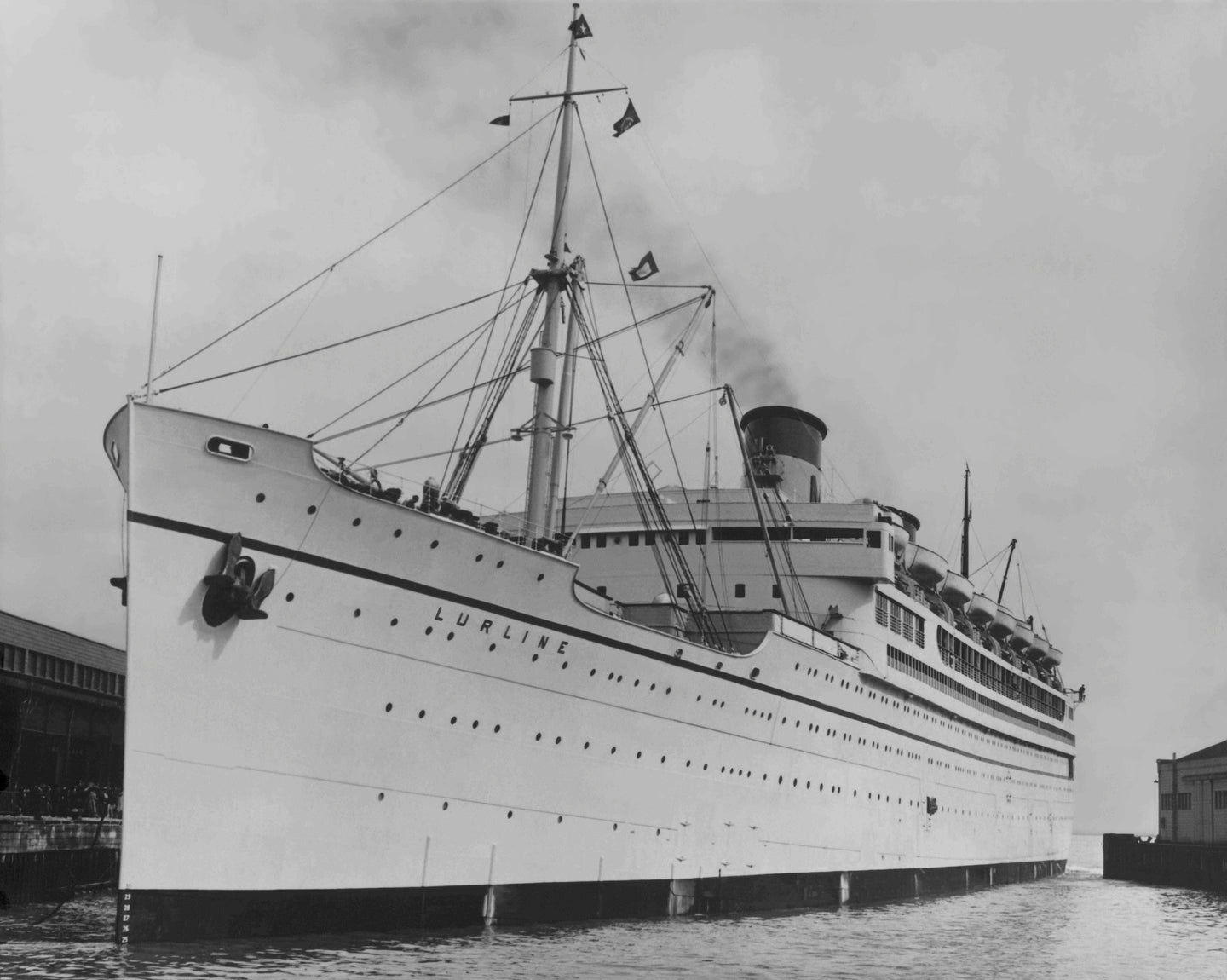 Vintage black and white photo of the S.S. Lurline at dock with view from bow. Smoke coming from front stack.