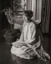Load image into Gallery viewer, Black and white photograph of Amelia Earhart wearing a silk kimono robe while sitting with a book in her lap and giving the camera her profile as she looks in the distance.