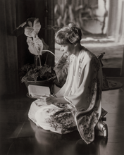 Load image into Gallery viewer, Black and white photograph of Amelia Earhart wearing a kimono robe, sitting on the floor, reading a book.