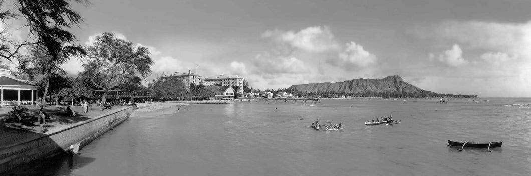 Black and white panoramic photograph of Waikiki Beach, Honolulu, Hawaii shoreline and Pacific Ocean with Diamond Head in the background.