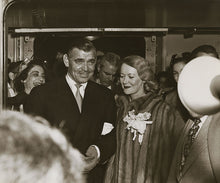 Load image into Gallery viewer, Black and white photograph of actor Clark Gable in a suit accompanying Lady Sylvia Ashley who is wearing a fur coat among a crowd of people on the Matson Lines cruise ship, Lurline.