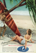 Load image into Gallery viewer, Matson Lines cruises travel advertisement featuring an Anton Bruehl photograph of man in white swim shorts holding a red surfboard in the shade of a tree looking at a woman in a white swimsuit reclining on the sand wearing a yellow flower lei and holding down a blue hat on the sand.