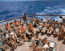 Load image into Gallery viewer, Color photograph of sunbathers reclining in deck chairs on the cruise ship, Lurline, with the ocean in the background.