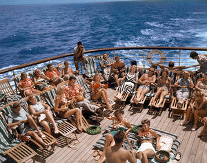 Color photograph of sunbathers reclining in deck chairs on the cruise ship, Lurline, with the ocean in the background.
