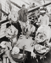 Load image into Gallery viewer, Black and white photograph of a group of people in the 1930s on the deck of a ship sitting at a table having tea. By photographer Edward Steichen.