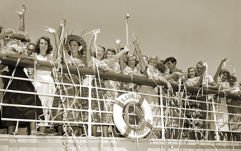 Black and white sepia photograph of passengers waving with streamers at the railing on the deck of the S.S. Lurline.