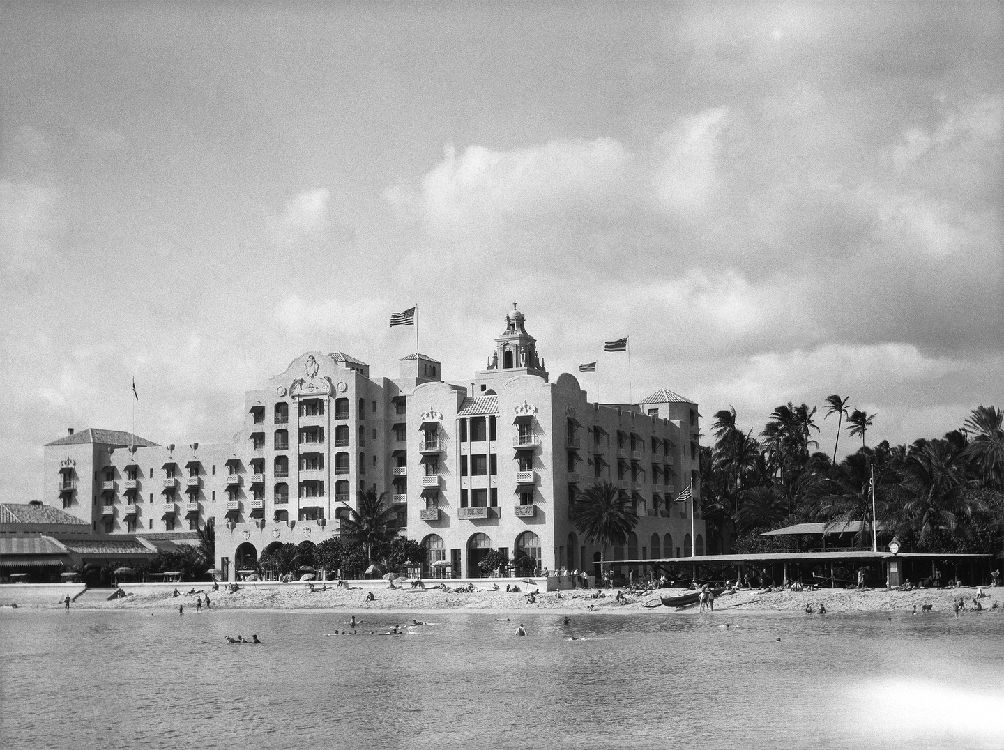 Black and white photograph of the Royal Hawaiian Hotel with Waikiki beach in front of it.