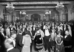 Black and white photograph of a festive crowd in a ballroom celebrating the opening of the Royal Hawaiian Hotel,  dressed in 1920s evening wear.
